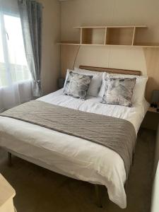 a bed with two pillows on it in a bedroom at Coastal caravan retreat in Brightlingsea