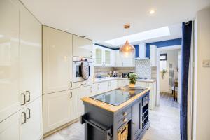 a kitchen with white cabinets and a blue island at Warwickshire Beautiful Cottage, 2 dbl bed Sleeps 4 by EMPOWER HOMES in Kenilworth