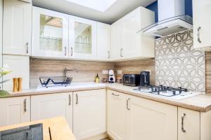 una cucina con armadi bianchi e lavandino di Warwickshire Beautiful Cottage, 2 dbl bed Sleeps 4 by EMPOWER HOMES a Kenilworth