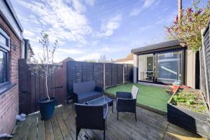 a backyard with a deck with chairs and a lawn at Warwickshire Beautiful Cottage, 2 dbl bed Sleeps 4 by EMPOWER HOMES in Kenilworth
