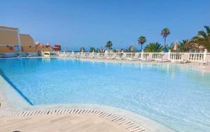 a large swimming pool with white chairs in a resort at Sea view el veril in Adeje