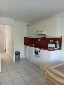 - une cuisine avec des placards blancs et un évier dans l'établissement Location appartement meublé bord de mer, à Fouesnant