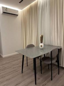 een eettafel met 2 stoelen en een vaas erop bij شقة انيقة غرفة نوم ومجلس وصالة in Buraydah