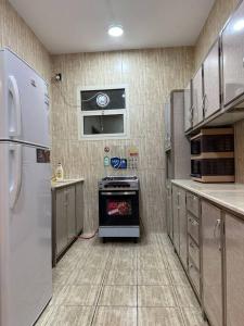 een keuken met een koelkast en een fornuis. bij شقة انيقة غرفة نوم ومجلس وصالة in Buraydah