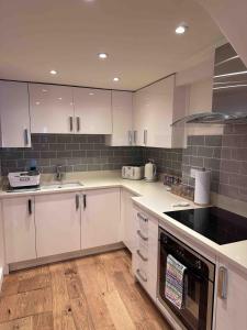 a kitchen with white cabinets and black appliances at Bramble cottage with free parking in Bridgnorth