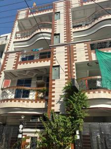 um edifício alto com uma árvore em frente em Entire House- Ground Floor- Raj Villa em Kanpur