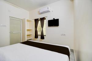 a white bedroom with a bed and a tv at OYO ALYSAN STAY in Bhubaneshwar