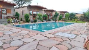 a swimming pool in front of a house at Emirishoi Cottages and Garden Bistro in Narok