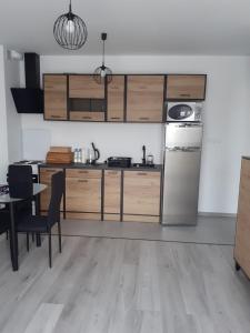 eine Küche mit Holzschränken, einem Tisch und einem Kühlschrank in der Unterkunft Apartament w Starym Młynie in Sobótka