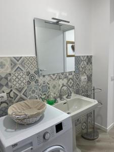 a bathroom with a sink and a mirror and a washing machine at The Tulip: 2 rooms apartment in Ronzo Chienis