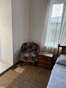 a bedroom with a chair next to a window at GuestHouse LILIA &Wine Celler in Tʼelavi