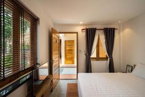 a bedroom with a bed and a window and a door at THE YARD, DUONG DONG, PHU QUOC in Phu Quoc