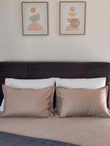 uma cama com duas almofadas e duas fotografias na parede em Sunny Apartment em Kali