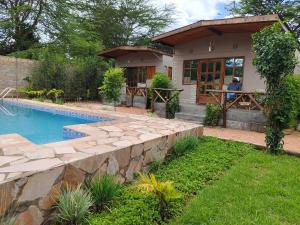 een huis met een zwembad in een tuin bij Emirishoi Cottages and Garden Bistro in Narok
