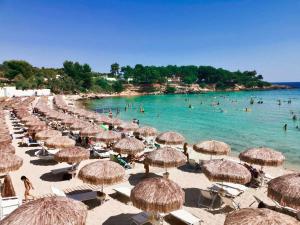 a beach with many straw umbrellas and people in the water at Alemà casa vacanze in Leporano