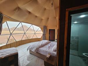 a bedroom with a bed and a view of the desert at Kylie magic camp in Wadi Rum