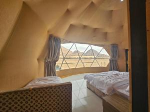 a bedroom with two beds and a large window at Kylie magic camp in Wadi Rum