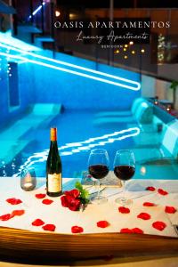 フィネストラットにあるAPARTAMENTOS OASIS DE LA CALAのスイミングプールの横のテーブルに置かれたワイン2杯とバラ