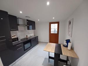 eine Küche mit schwarzen Schränken und einem Holztisch in der Unterkunft Appartement Jacuzzi /billard in Voiron