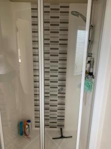 a shower with a glass door in a bathroom at Newbeach Holiday Park - Greenfields in Dymchurch