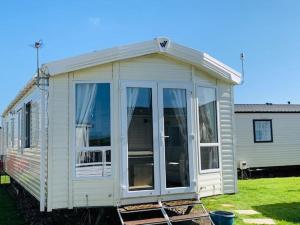 a white house with large glass doors in a yard at Newbeach Holiday Park - Greenfields in Dymchurch