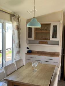 a kitchen with a wooden table with chairs and aendant light at Newbeach Holiday Park - Greenfields in Dymchurch