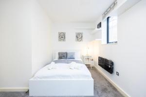 a white bedroom with a bed and a tv at Modern 1 BR Apartment Near Shoreditch - 10 Min Walk in London