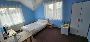 Una habitación azul con una cama, un escritorio y ventanas. en Hotelik u Sąsiada, en Olsztyn