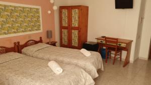 2 camas en una habitación con escritorio y mesa en Hotel 4 Mori, en Cagliari