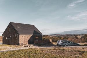 a barn with a car parked in front of it at Nomads' Hill - dom z widokiem na góry in Poraż