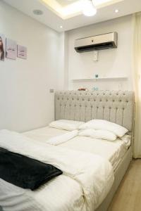 1 dormitorio con 2 camas con sábanas blancas en مدينه 15مايو en Ḩulwān
