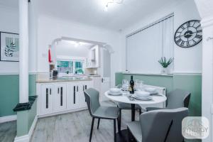 a kitchen with a table and chairs and a clock on the wall at Jade House, Manchester - by Synergy Estates in Manchester