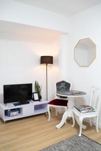 een woonkamer met een tv en een tafel en stoelen bij Porto Ribeira RC Traseiras in Porto