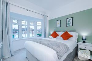 a bedroom with a large bed with orange pillows at Jade House, Manchester - by Synergy Estates in Manchester