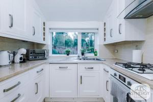 a white kitchen with a sink and a window at Jade House, Manchester - by Synergy Estates in Manchester