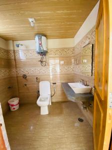 a bathroom with a toilet and a sink at Timber Hill Hotel in Manāli