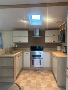 una cucina con mobili bianchi e un forno a piano cottura di Caravan, Whitstable a Seasalter