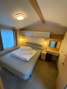 una piccola camera da letto con un letto e una scrivania di Caravan, Whitstable a Seasalter Altre 2 foto