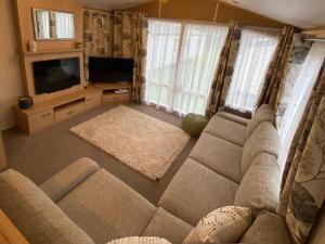 un soggiorno con un divano e una televisione di Caravan, Whitstable a Seasalter