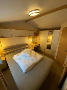 un grande letto bianco in una piccola stanza di Caravan, Whitstable a Seasalter