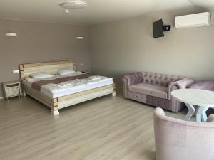 ein Schlafzimmer mit einem Bett, einem Sofa und einem Tisch in der Unterkunft Chorna Skelya Resort & Wellness in Wynohradiw