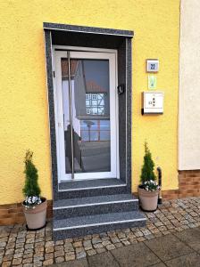 ein gelbes Haus mit einer Tür und zwei Topfpflanzen in der Unterkunft Ferienhaus Strauss nahe der Kyffhäuser Therme in Bad Frankenhausen