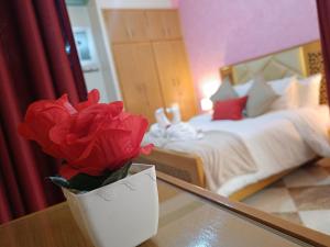 un vase avec une rose rouge sur une table dans une chambre dans l'établissement Aljazeera apartment, à Tanger