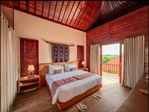 a bedroom with a bed and a large window at Odessa Village by Pramana Villas in Gianyar