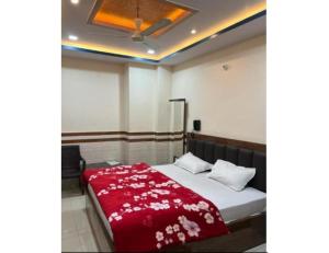a bedroom with a bed with a red blanket at Hotel Shree Galaxy, Kanpur in Kānpur