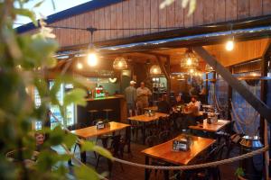 un restaurante con mesas de madera y gente sentada a su lado en Big Foot by MANGO Food&Bar, en Karwia