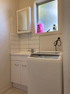 una piccola cucina con lavatrice e finestra di epsom tidy white house ad Auckland