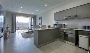 a kitchen with stainless steel appliances and a living room at StayEasy Lux Apartment in Edenvale