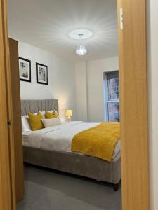 1 dormitorio con 1 cama grande con almohadas amarillas en Luxury Lakeview Apartment, en Dartford