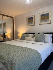 una camera da letto con un grande letto bianco con cuscini di Luxury Lakeview Apartment a Dartford